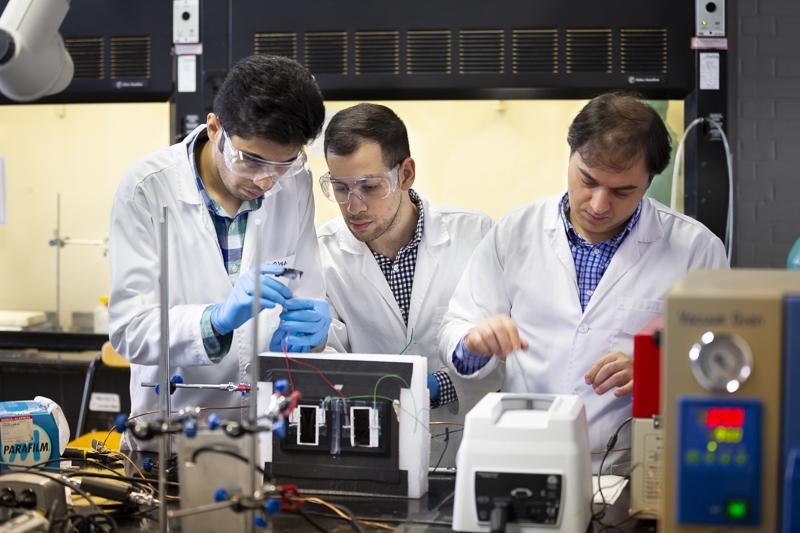 Graduate students work in an electrical engineering lab with their professor.